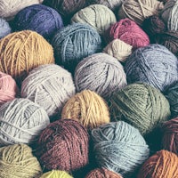 many colorful balls of yarn are arranged in a pile