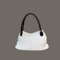 a white crocheted handbag on a gray background