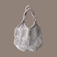 a grey crocheted bag on a brown background