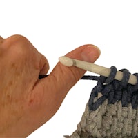 a person holding a crochet hook to a crocheted stitch