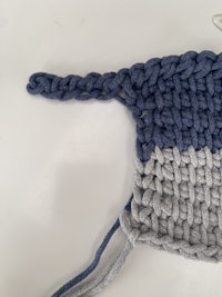 a blue and grey crocheted hat with a hook on it