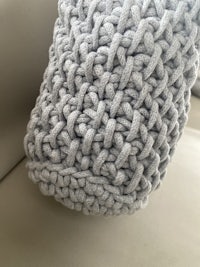 a grey knitted blanket on a couch