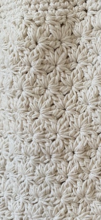 a close up of a white crocheted pillow