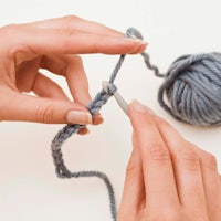 a person is knitting a ball of yarn with a crochet hook