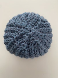 a blue knitted beanie on a white surface